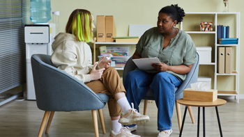 young adult woman with green hair having a chat with support worker